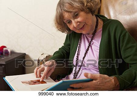 A senior woman pointing at a photograph in a photo album View Large Photo Image Stock Image - A senior woman pointing at a photograph in a photo album. Fotosearch