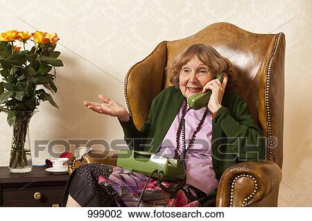A senior woman talking on the phone in her living room View Large Photo Image Stock Image - A senior woman talking on the phone in her living room. Fotosearch