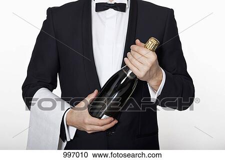 Stock Image - A sommelier holding a bottle of champagne. Fotosearch