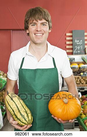 Stock Image - A stocker holding two varieties of winter squash. Fotosearch