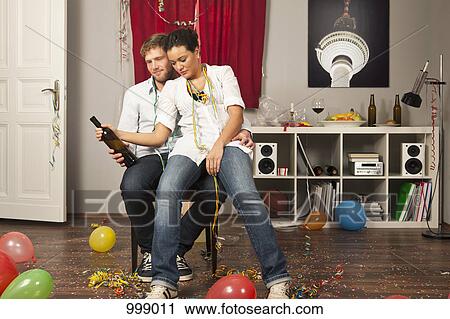 Stock Image - A tipsy woman sitting on her boyfriend's lap. Fotosearch