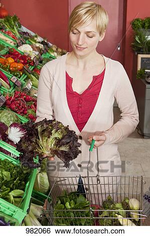 A woman contemplating a head of red leaf lettuce View Large Photo Image Stock Photograph - A woman contemplating a head of red leaf lettuce. Fotosearch