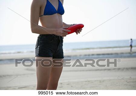 A woman holding a plastic disc at the beach, midsection View Large Photo Image Stock Photography - A woman holding a plastic disc at the beach, midsection. Fotosearch