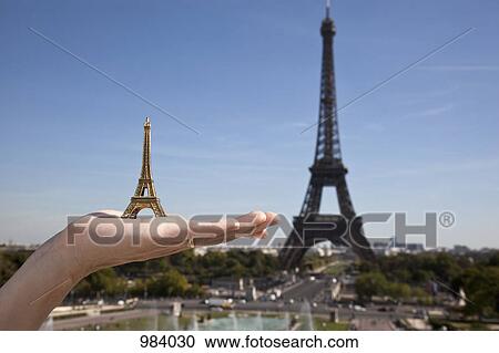 A woman holding an Eiffel Tower replica souvenir next to the real Eiffel Tower, focus on hand View Large Photo Image Stock Image - A woman holding an Eiffel Tower replica souvenir next to the real Eiffel Tower, focus on hand. Fotosearch