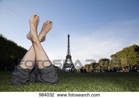 A woman laying in grass by Eiffel Tower, focus on feet View Large Photo Image Stock Image - A woman laying in grass by Eiffel Tower, focus on feet. Fotosearch
