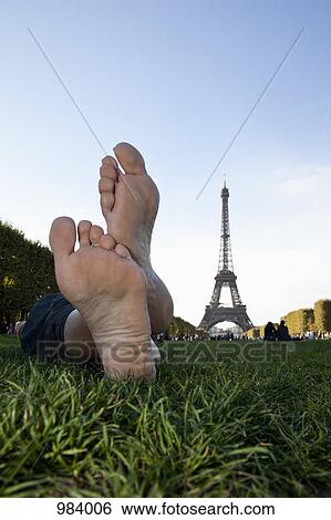 A woman laying in grass by Eiffel Tower, focus on feet View Large Photo Image Stock Photograph - A woman laying in grass by Eiffel Tower, focus on feet. Fotosearch