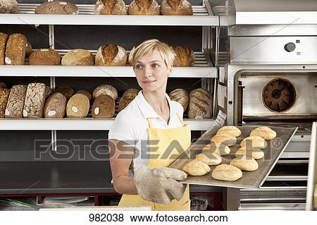 A woman pulling a tray of freshly baked rolls in a bakery View Large Photo Image Stock Photo - A woman pulling a tray of freshly baked rolls in a bakery. Fotosearch