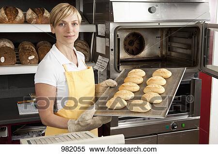 A woman pulling a tray of freshly baked rolls in a bakery View Large Photo Image Stock Photography - A woman pulling a tray of freshly baked rolls in a bakery. Fotosearch
