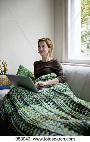 A woman reclining on a couch using a laptop View Large Photo Image Stock Image - A woman reclining on a couch using a laptop. Fotosearch