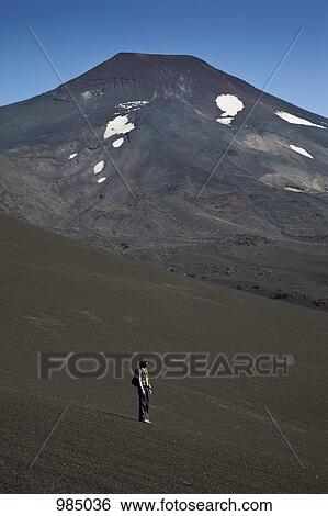 Stock Photograph - A woman standing on Lonquimay Volcano, Patagonia, Chile. Fotosearch