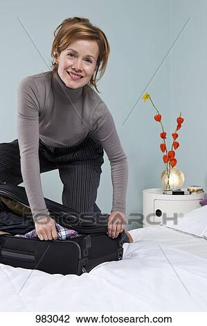 A woman trying to close an overflowing suitcase View Large Photo Image Stock Image - A woman trying to close an overflowing suitcase. Fotosearch