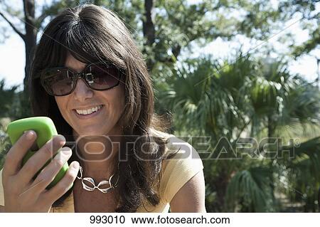 A woman using a smart phone, outdoors View Large Photo Image Stock Image - A woman using a smart phone, outdoors. Fotosearch
