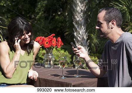 A woman using her mobile while her boyfriend text messages on a backyard deck View Large Photo Image Stock Image - A woman using her mobile while her boyfriend text messages on a backyard deck. Fotosearch