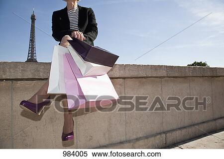 A woman with four shopping bags sitting on a wall in Paris, France View Large Photo Image Stock Photography - A woman with four shopping bags sitting on a wall in Paris, France. Fotosearch