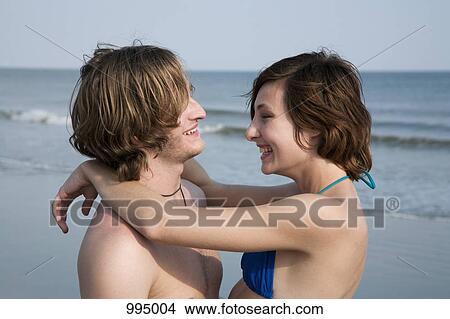 A young affectionate couple laughing at the beach View Large Photo Image Picture - A young affectionate couple laughing at the beach. Fotosearch