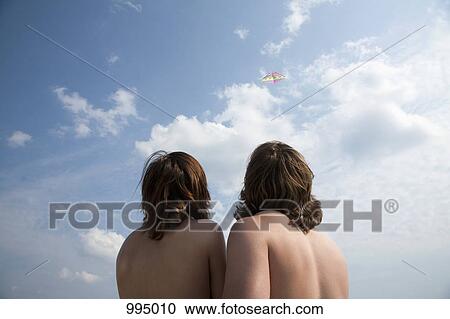 A young couple flying a kite, rear view View Large Photo Image Stock Image - A young couple flying a kite, rear view. Fotosearch