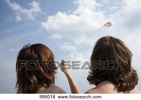 A young couple flying a kite, rear view View Large Photo Image Stock Photo - A young couple flying a kite, rear view. Fotosearch