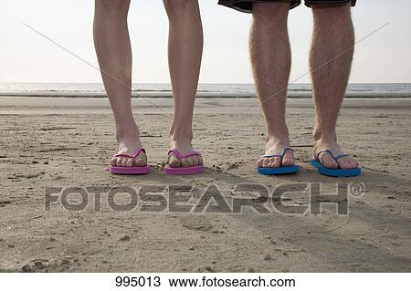 A young couple wearing flip-flops at the beach, low section View Large Photo Image Stock Image - A young couple wearing flip-flops at the beach, low section. Fotosearch