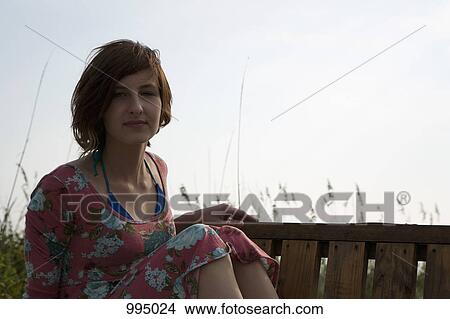 Picture - A young woman sitting on a bench. Fotosearch