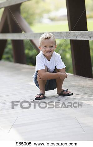Boy crouching on bridge View Large Photo Image Stock Photography - Boy crouching on bridge. Fotosearch