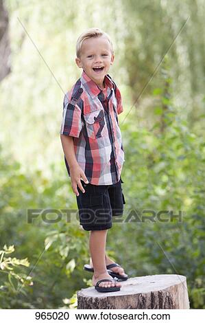 Stock Image - Boy on tree stump. Fotosearch