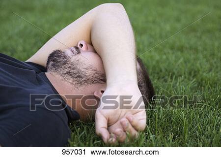 Close-up man laying on grass arm on face View Large Photo Image Stock Image - Close-up man laying on grass arm on face. Fotosearch