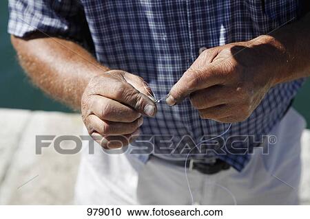 Detail of a man tying a fishing line to a hook View Large Photo Image Stock Image - Detail of a man tying a fishing line to a hook. Fotosearch