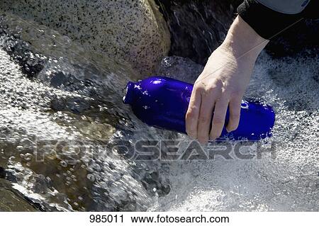 Detail of a person filling a drink bottle in a river View Large Photo Image Stock Image - Detail of a person filling a drink bottle in a river. Fotosearch