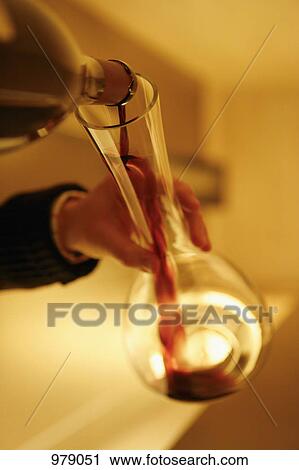 Stock Image - Detail of a person pouring red wine into a decanter. Fotosearch