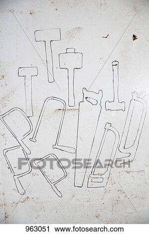 Stock Image - Detail of drawn outlines of hand tools on a wall. Fotosearch