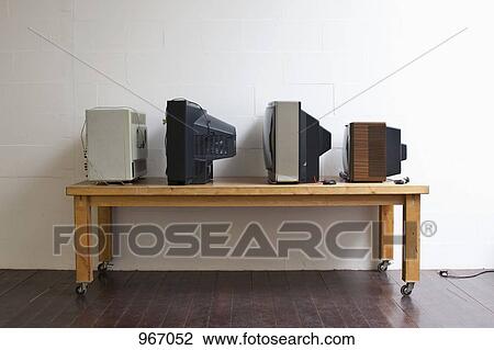 Stock Image - Four televisions on a table. Fotosearch