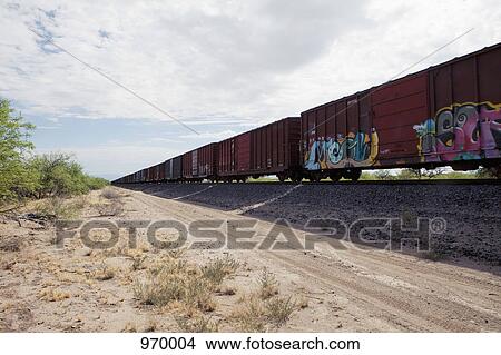 Picture - Freight train next to a dirt road. Fotosearch