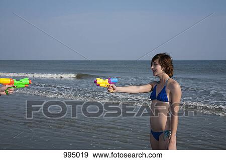 Friends playing with squirt guns at the beach View Large Photo Image Stock Photo - Friends playing with squirt guns at the beach. Fotosearch