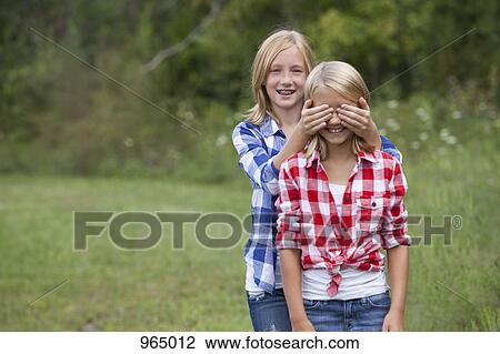 Girl covering friend's eyes View Large Photo Image Stock Image - Girl covering friend's eyes. Fotosearch