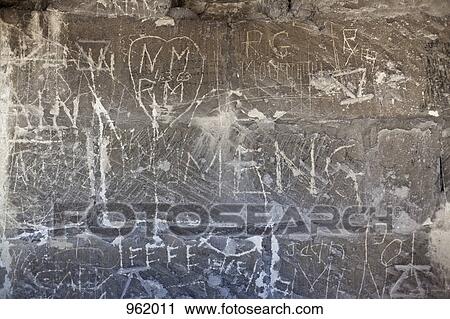 Stock Image - Handwritten graffiti etched into a stone wall. Fotosearch