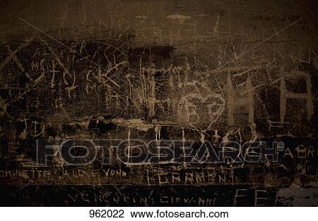 Stock Image - Handwritten graffiti etched into a stone wall. Fotosearch