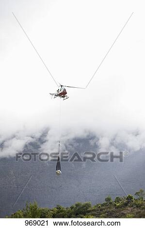 Helicopter transporting supplies over land View Large Photo Image Stock Image - Helicopter transporting supplies over land . Fotosearch