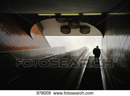 Low angle view of a man on a subway escalator View Large Photo Image Stock Photo - Low angle view of a man on a subway escalator. Fotosearch