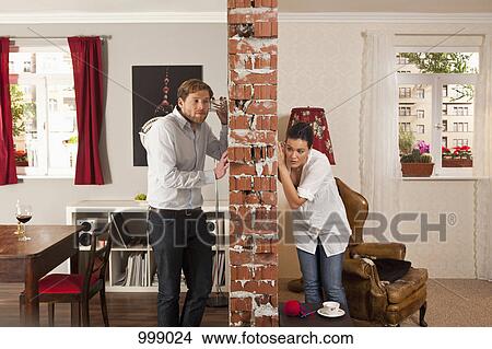 Man and woman listening on either side of wall with drinking glasses View Large Photo Image Picture - Man and woman listening on either side of wall with drinking glasses. Fotosearch
