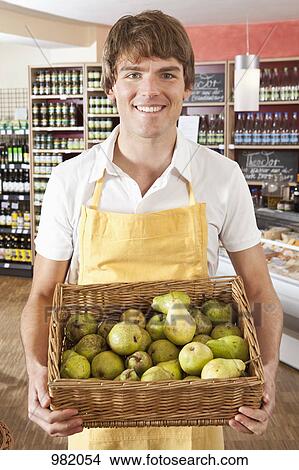 Portrait of a supermarket sales clerk holding a basket of pears View Large Photo Image Picture - Portrait of a supermarket sales clerk holding a basket of pears. Fotosearch