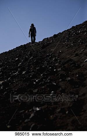 Stock Photography - Rear view of a woman hiking up Lonquimay Volcano, Patagonia, Chile. Fotosearch