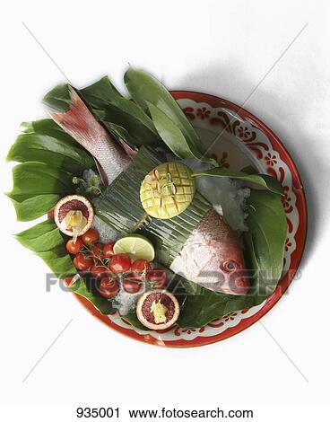 Stock Image - Red snapper wrapped in a banana leaf with garnish. Fotosearch
