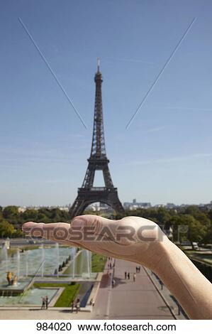 The optical illusion of a woman holding the Eiffel Tower in her hand, focus on hand View Large Photo Image Stock Image - The optical illusion of a woman holding the Eiffel Tower in her hand, focus on hand. Fotosearch