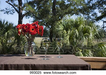 Two glasses of white wine and a vase of Gerbera daisies on a table, outdoors View Large Photo Image Stock Photography - Two glasses of white wine and a vase of Gerbera daisies on a table, outdoors. Fotosearch