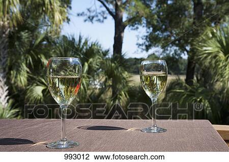 Two glasses of white wine on a table, outdoors View Large Photo Image Stock Image - Two glasses of white wine on a table, outdoors. Fotosearch