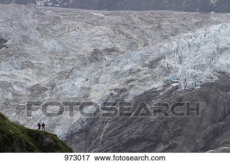 Two hikers looking at a glacier View Large Photo Image Stock Photo - Two hikers looking at a glacier. Fotosearch