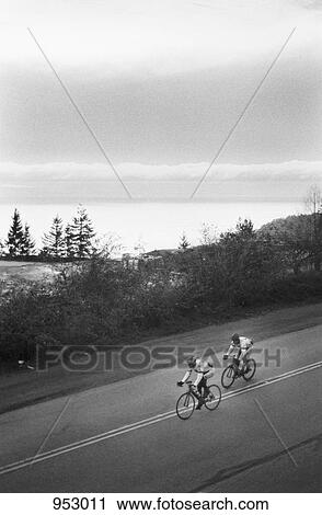 Two men riding racing bicycles, rural setting View Large Photo Image Stock Image - Two men riding racing bicycles, rural setting. Fotosearch