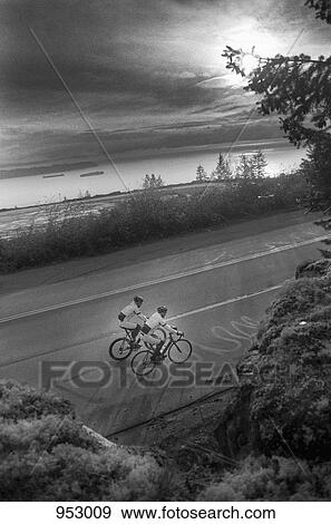 Two men riding racing bicycles, rural setting View Large Photo Image Stock Photo - Two men riding racing bicycles, rural setting. Fotosearch