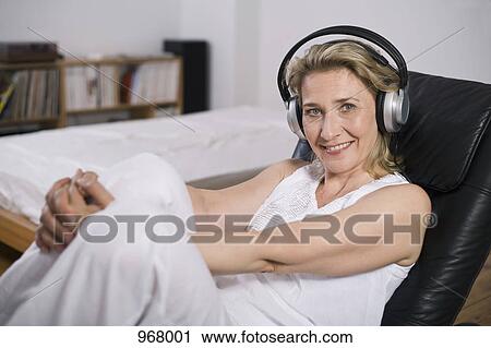 Woman lounging listening to music View Large Photo Image Stock Image - Woman lounging listening to music. Fotosearch