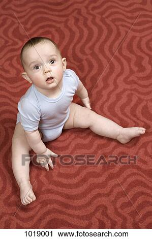 A baby boy sitting on a patterned carpet View Large Photo Image Stock Image - A baby boy sitting on a patterned carpet. Fotosearch